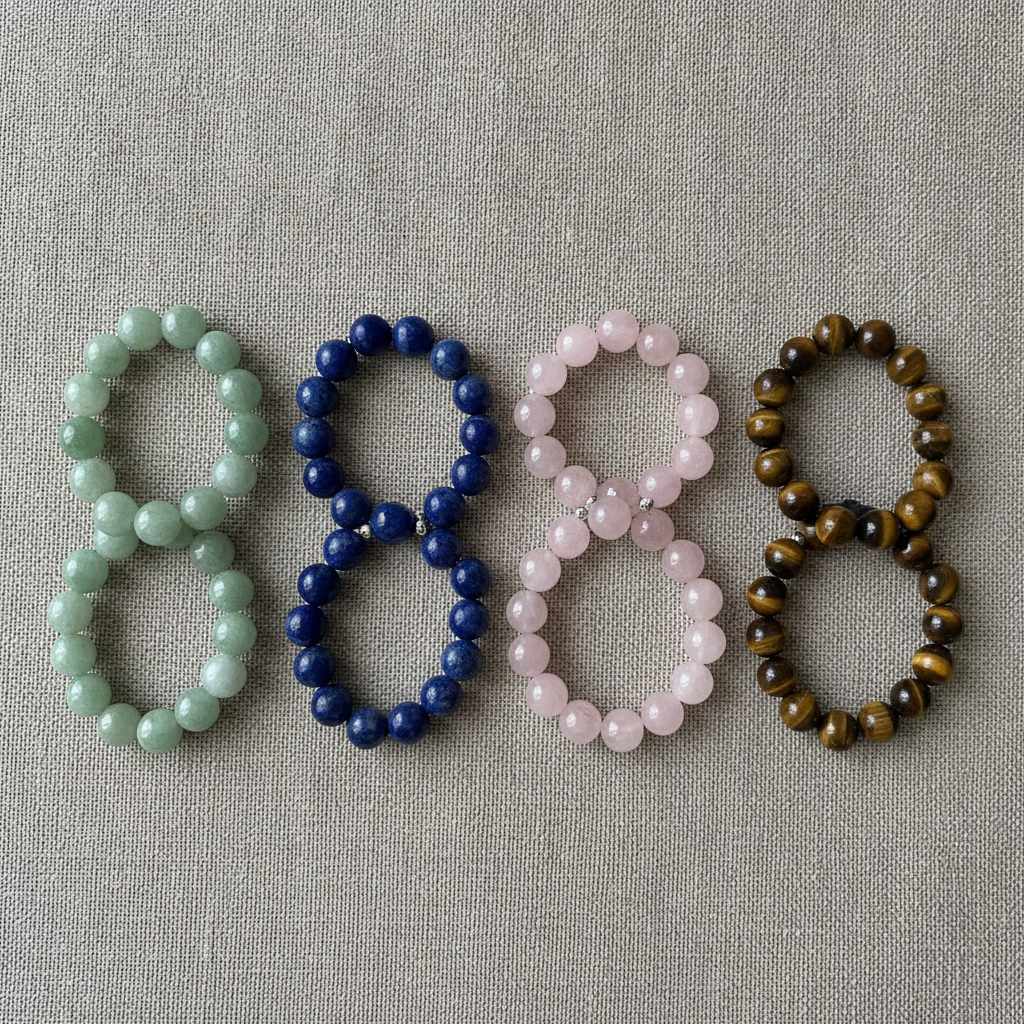 Bracelets de pierres naturelles classés par couleur sur fond de lin neutre